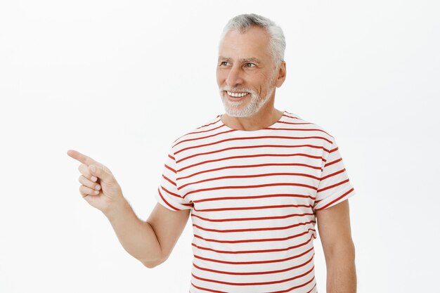 Heureux vieil homme en t-shirt à la recherche et pointant vers la gauche