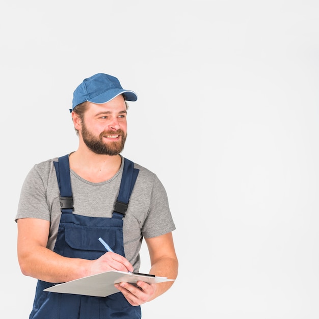 Photo gratuite heureux wan en casquette et écriture générale sur le presse-papiers