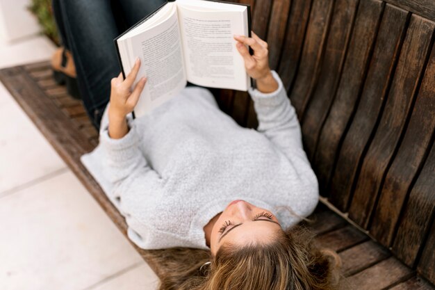 High angle blonde woman reading sur un banc