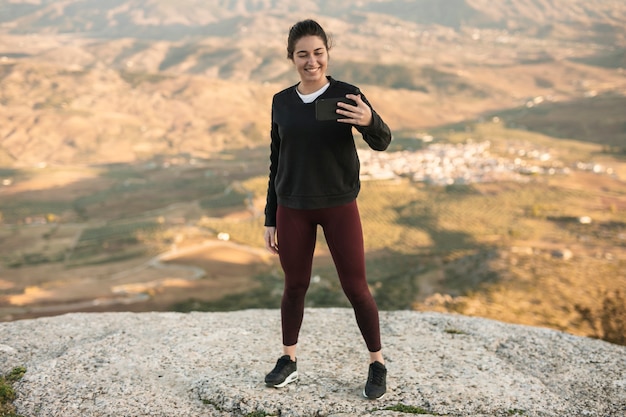 High angle jeune femme sur la montagne prenant selfie