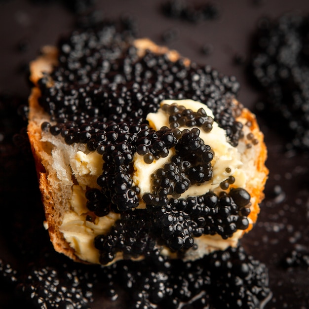 High angle view caviar noir sur pain sur fond sombre.