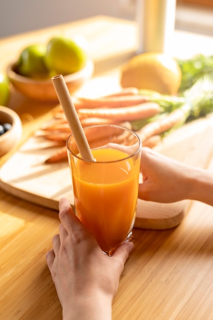 High angle woman hands holding glass avec jus de carotte