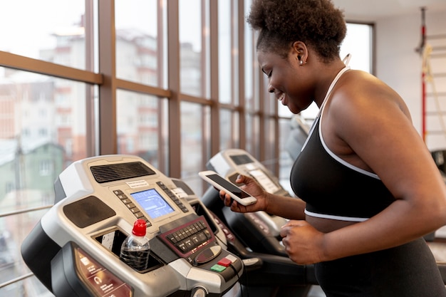 High angle woman on treadmill using mobile