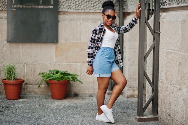 Hip hop fille afro-américaine sur lunettes de soleil et short en jean Portrait de mode de rue décontractée d'une femme noire