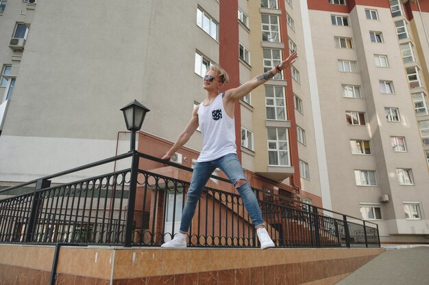 Hipster beau homme blond dans des vêtements d'été élégants dans la rue