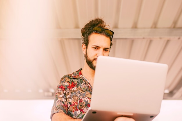 Photo gratuite hipster concentré travaillant sur un ordinateur portable à l'extérieur