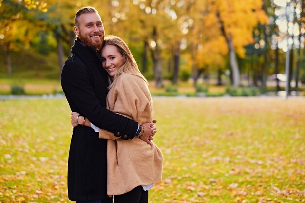 Histoire d'amour d'automne. Un homme rousse séduisant embrasse une jolie femme blonde sur fond de nature sauvage d'automne.