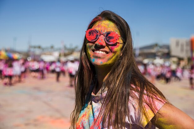 Holi couleur sur le visage de la femme en regardant la caméra