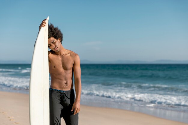 Homme adulte afro-américain fatigué après le surf