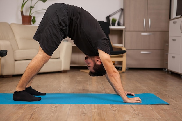 Homme adulte faisant du yoga Dolphin pose dans sa routine d'entraînement. Entraînement sain.