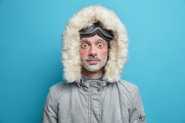 Photo gratuite un homme adulte gelé choqué regarde a les yeux sortis du visage rouge gelé par temps glacial