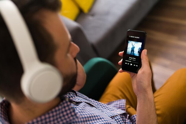 Homme adulte jouant une chanson sur son smartphone et écoutant de la musique avec des écouteurs sans fil