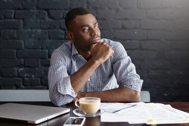 Homme d'affaires afro-américain sérieux prenant un café au café