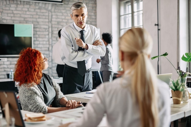 Homme d'affaires d'âge moyen discutant avec ses collègues féminines au bureau