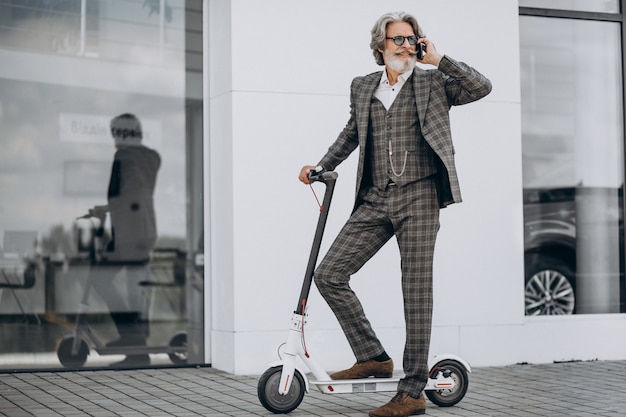 Homme d'affaires d'âge moyen en scooter dans un costume élégant