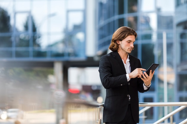 Homme d'affaires à l'aide de sa tablette à l'extérieur