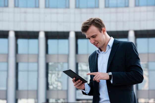 Homme d'affaires à l'aide de tablette près du bâtiment