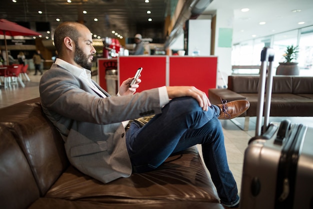 Photo gratuite homme d'affaires à l'aide de téléphone portable dans la zone d'attente