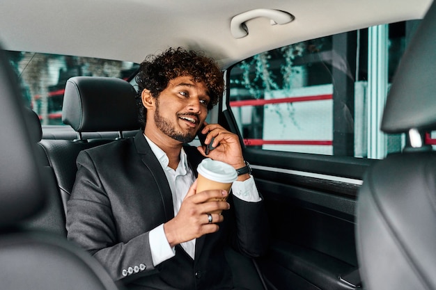 Un homme d'affaires aux cheveux bouclés discutera de la conférence dans la voiture.