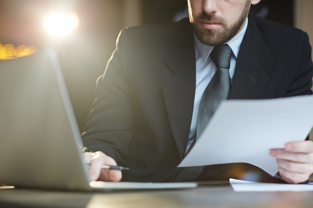 Homme d'affaires barbu travaillant avec des documents au bureau