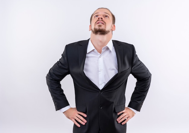 Homme d'affaires beau gêné portant costume à la recherche debout sur fond blanc