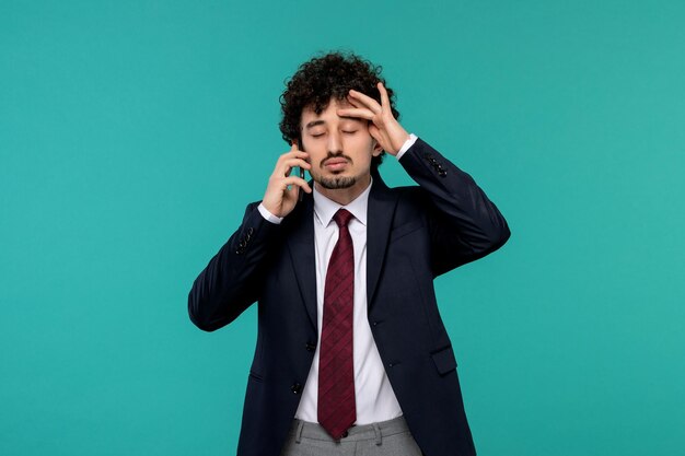 Homme d'affaires beau jeune homme mignon en costume noir et cravate rouge agacé et fatigué au téléphone