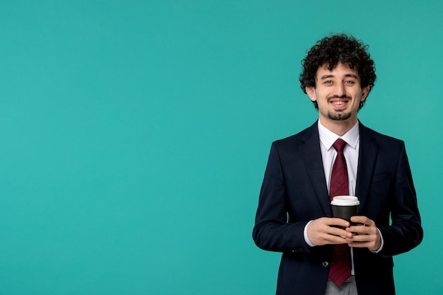 Homme d'affaires beau jeune homme mignon en costume noir et cravate rouge tenant joyeusement une tasse de café en papier