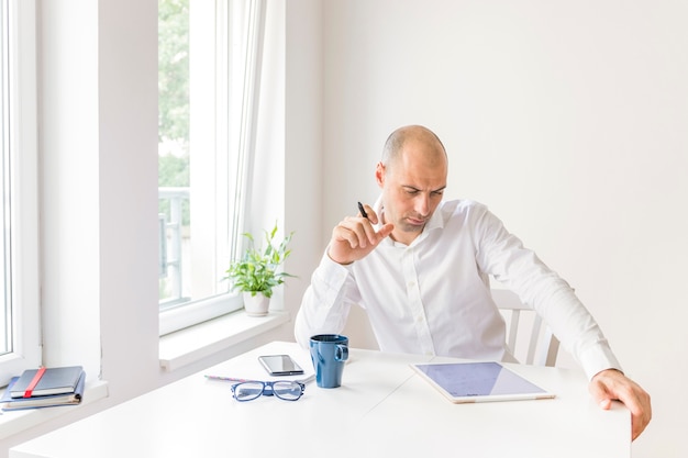 Homme d&#39;affaires bien pensé en regardant tablette numérique graphique sur le lieu de travail