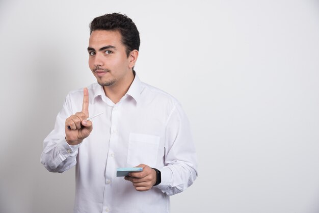 Homme d'affaires avec des blocs-notes faisant signe sur fond blanc.