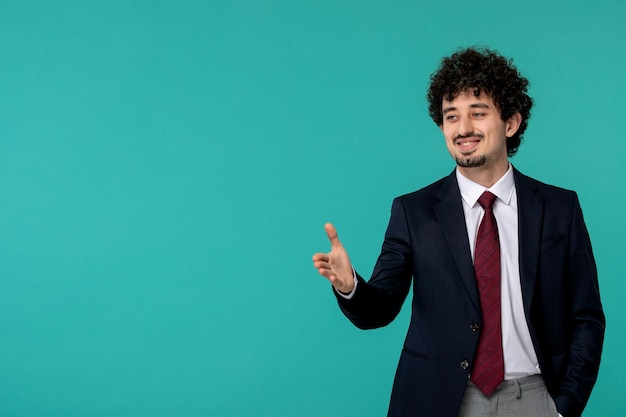 Homme d'affaires bouclé mignon beau mec en costume noir et cravate rouge souriant et donnant la poignée de main