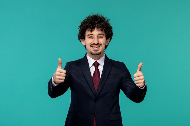 Homme d'affaires bouclé mignon beau mec en costume noir montrant un bon geste et souriant