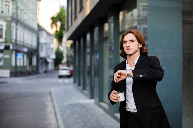 Homme d'affaires avec café en regardant sa montre