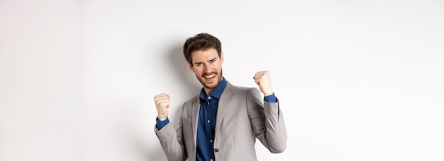 Homme d'affaires chanceux gagnant un prix en argent dire oui et souriant excité faire signe de pompe de poing pour célébrer v