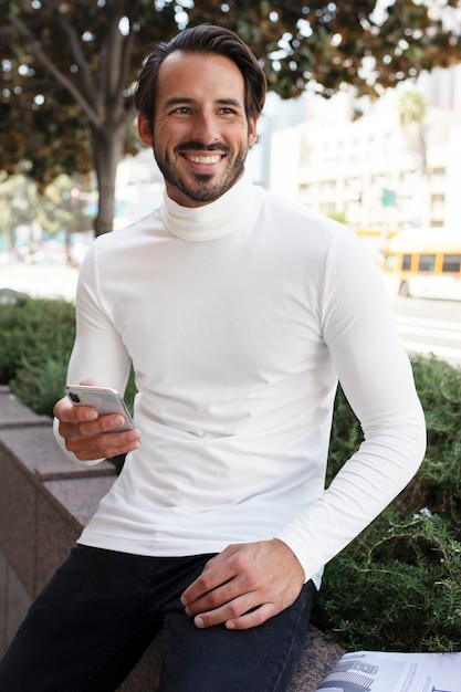 Photo gratuite homme d'affaires à col roulé assis et souriant dans la ville