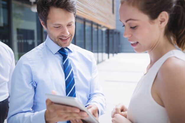 Homme d'affaires et collègue discutant sur tablette numérique