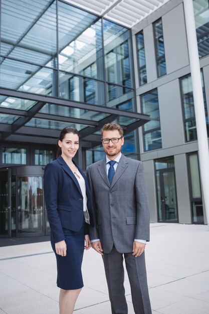 Homme d'affaires confiant avec un collègue debout à l'extérieur de l'immeuble de bureaux