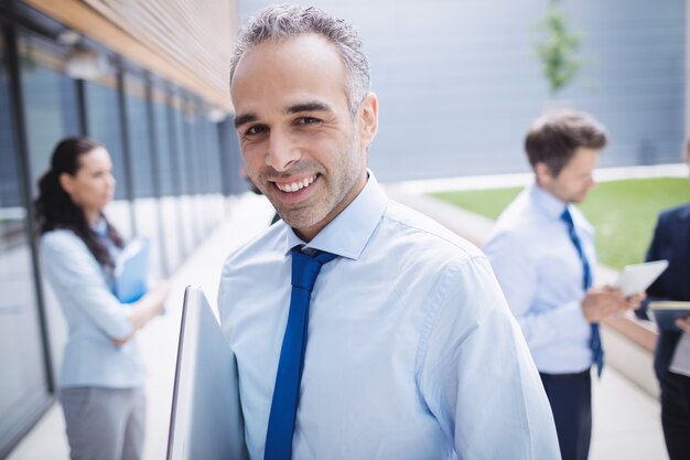 Homme d'affaires confiant souriant à l'extérieur de l'immeuble de bureaux