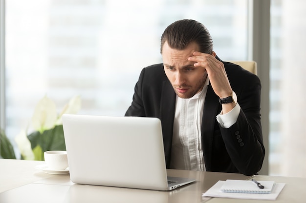 Photo gratuite homme d'affaires confus bouleversé regardant l'écran d'un ordinateur portable