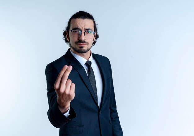 Homme d'affaires en costume noir et lunettes à l'avant avec un visage sérieux montrant deux doigts debout sur un mur blanc