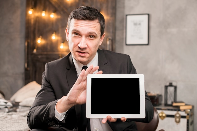 Homme d&#39;affaires en costume présentant une tablette