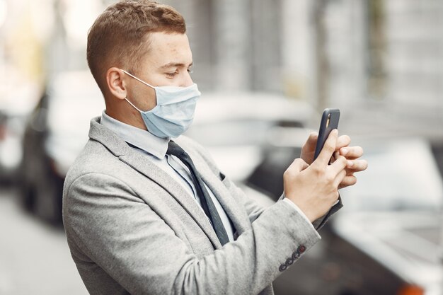 Homme d'affaires dans une ville. Personne dans un masque. Guy avec téléphone.