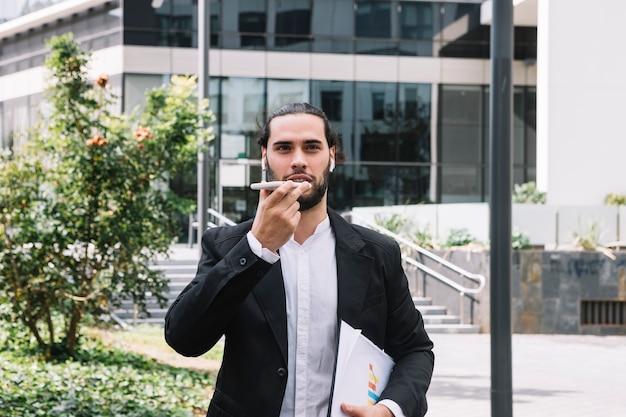 Homme d&#39;affaires debout à l&#39;extérieur de l&#39;immeuble de bureaux parlant sur haut-parleur