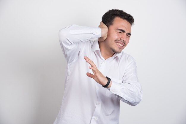 Homme d'affaires debout sur fond blanc tenant ses oreilles.