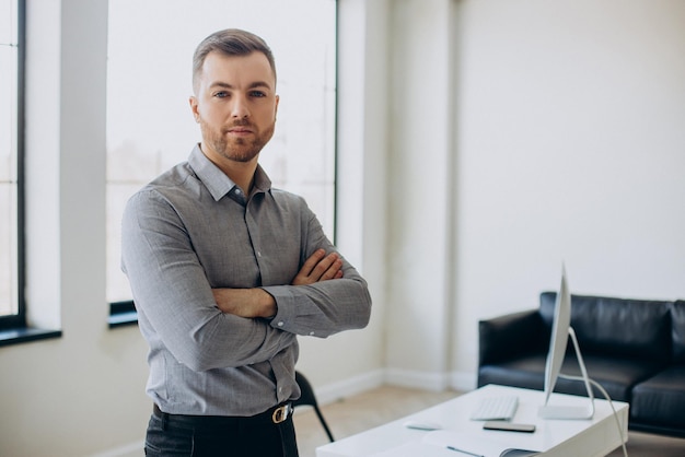 Photo gratuite homme d'affaires debout près du bureau au bureau