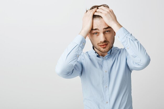 Homme d'affaires en détresse et troublé tenant les mains sur la tête et l'air désespéré