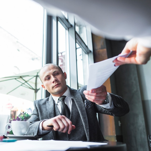 Photo gratuite homme d'affaires donnant un document à son partenaire dans un café