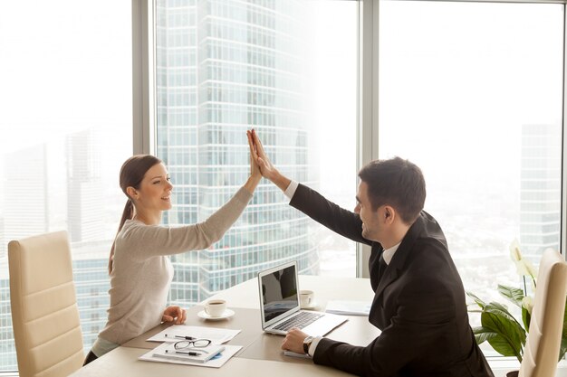 Homme d&#39;affaires donnant une femme d&#39;affaires haute cinq au bureau