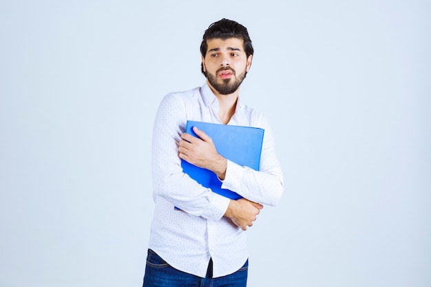 Un homme d'affaires donnant des poses avec un dossier de rapport bleu