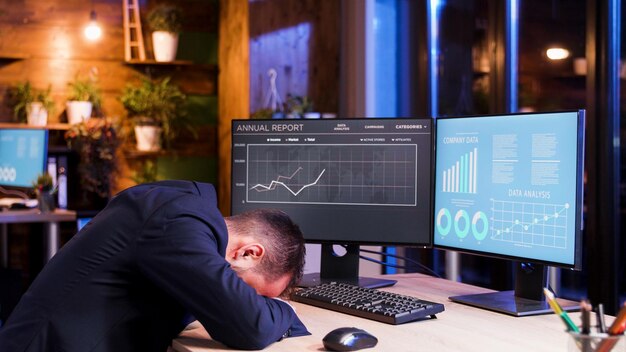 Homme d'affaires dormant la tête sur la table du bureau. Clair de lune et patron fatigué