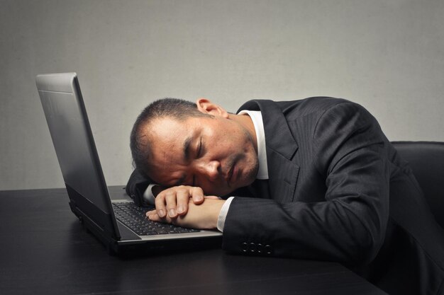 homme d'affaires dort sur un ordinateur ouvert